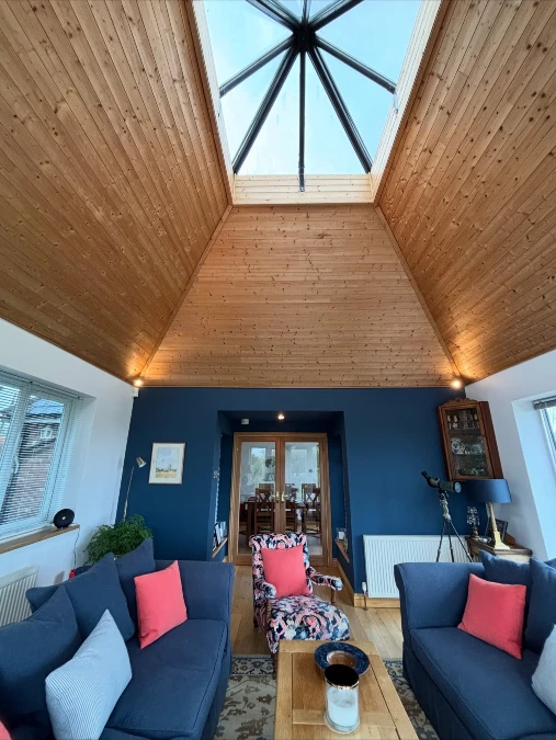 Navy Sofas And Coral Pillows Under A Vaulted Wood Ceiling